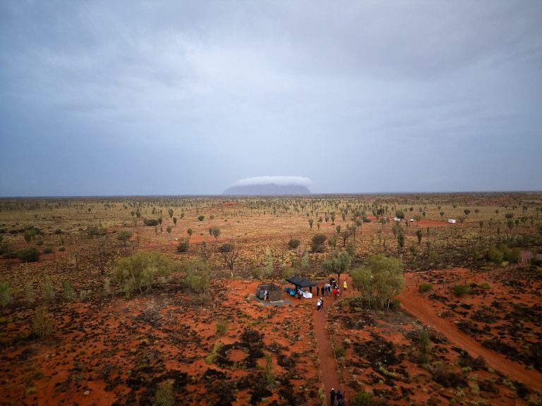 Silversea guests at Field of Lights with Uluru in the distance covered in cloud