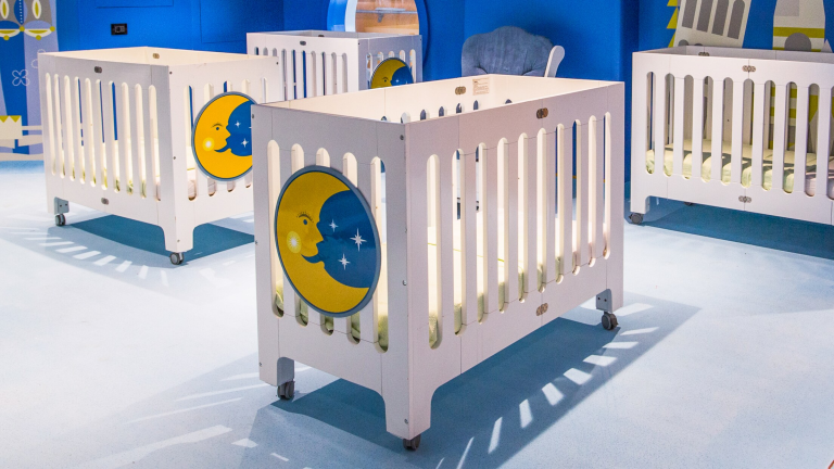 A room with cribs that are decorated with moons and stars, at Its a Small World Nursery