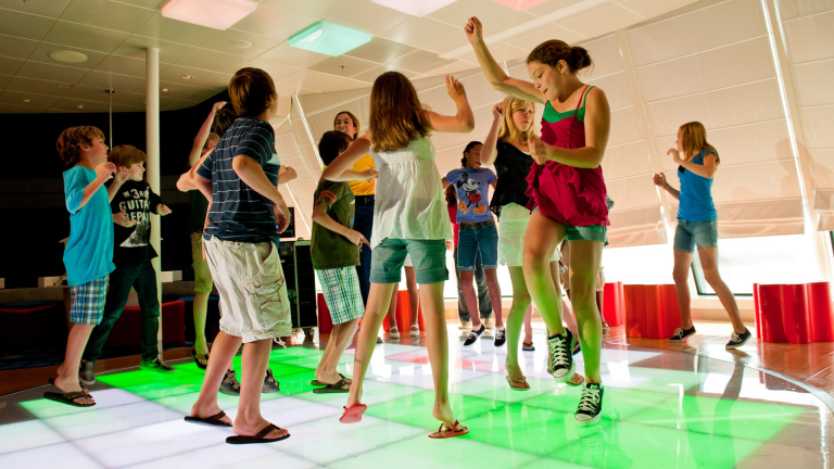 Tween kids talk on comfortable lounge chairs with flat screen monitors in the background_edge